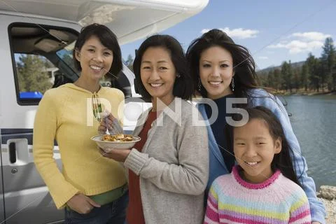 Three-generation of women eating breakfast outside of RV at lake Stock Photos