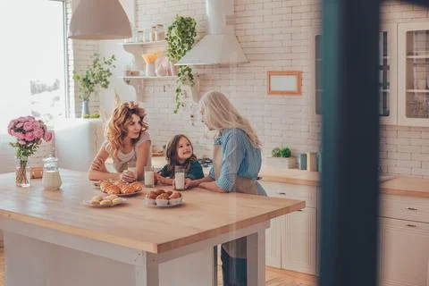 Three generations family talking on the kitchen with milk and cookies Stock Photos