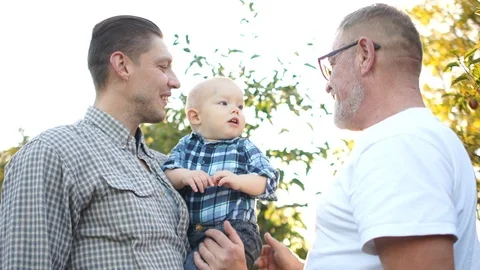 Three generations of the same family have fun in the apple orchard at sunset Stock Footage 119009741