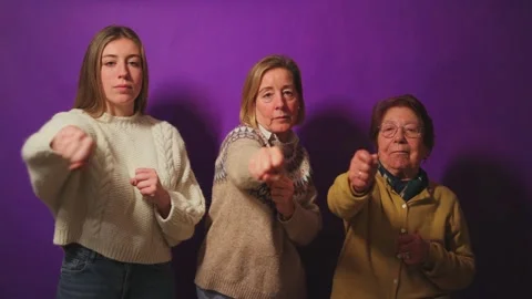 Three generations of women punching forward on purple background Stock Footage 296711675