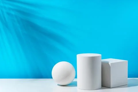 Three geometric shapes arranged on a table against a bright blue background Foto stock