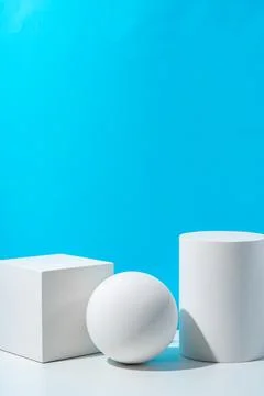 Three geometric shapes arranged on a table against a bright blue background Foto stock