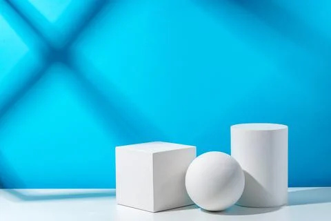 Three geometric shapes arranged on a table against a bright blue background Foto stock