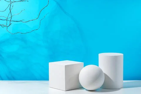 Three geometric shapes arranged on a table against a bright blue background Foto stock