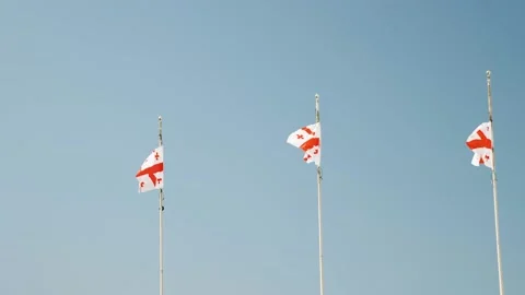 Three Georgian flags developing in the wind. In the background is a blue sky Stock Footage 217974102