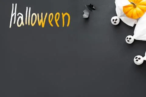 Three ghosts, pumpkin, bat and word halloween on black background, concept of Stock Photos