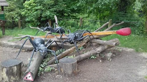 Three giant statues of black forest ants and a match with red tip over a pi.. Stock Photos