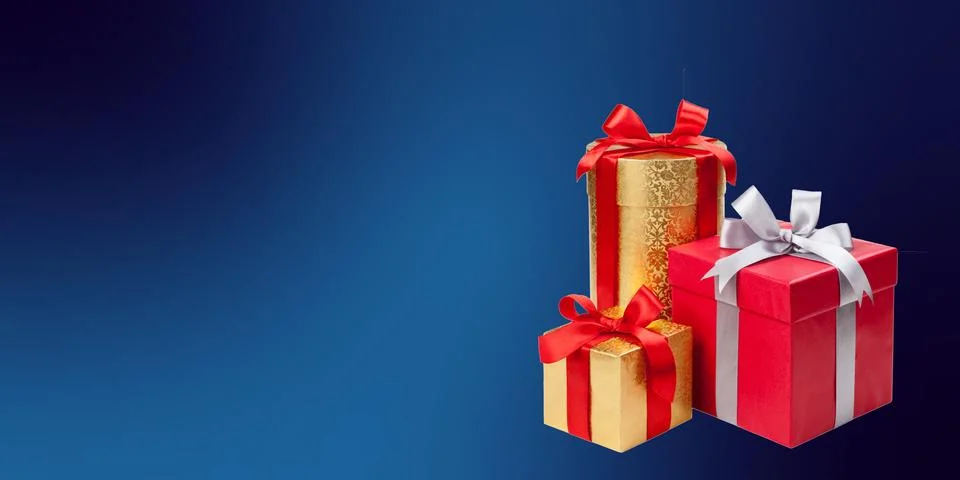 Three gift boxes are arranged against a dark blue gradient background. One box i Stock Photos