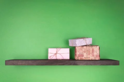 Three gift boxes of different colors arranged in a group on a black shelf set Stock Photos