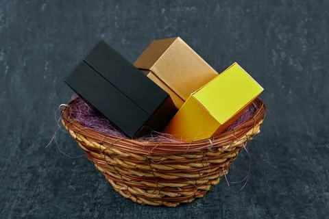 Three gift boxes of different colors in a wicker basket Stock Photos