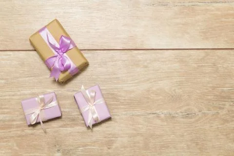 Three gift boxes with purple ribbons on a wooden table. Stock Photos