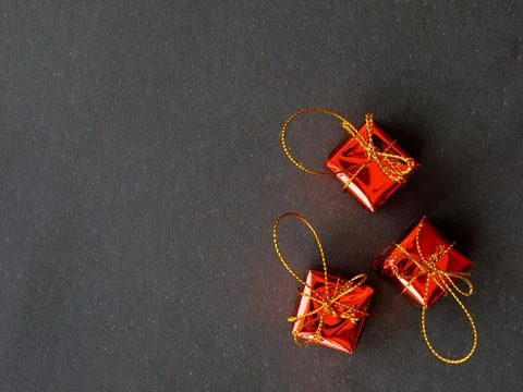 Three gift boxes wrapped in red paper tied with golden bow on black backgroun Stock Photos