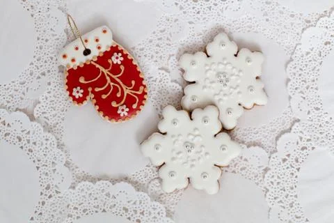 Three gingerbread cookies in the shape of red mitten and two snowflakes on a Stock Photos