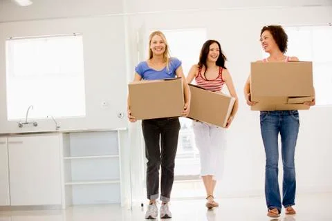 Three girl friends moving into new home smiling Stock Photos