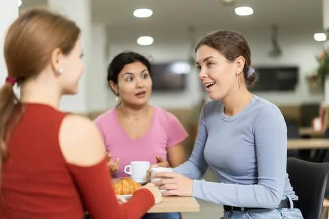 Three girlfriend chatting over coffee and croissant in cafeteria Stock-Fotos