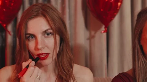 Three girlfriends applying bold red lipstick prepare for a festive Valentines Stock Footage 289791611