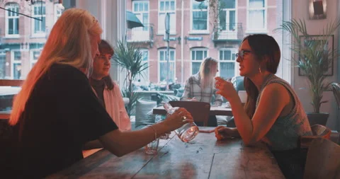 Three girlfriends talking and having drinks at the table Stock Footage 203582893