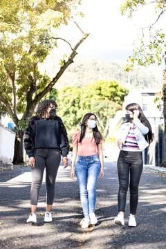 Three girlfriends using face mask and walking Stock Photos