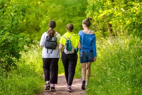 Three girlfriends walk along a path in the Park Stock-Fotos