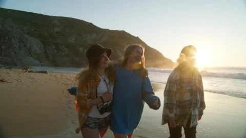 Three girlfriends walk on beach at sunset Stock Footage 254287844