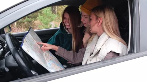 Three girls are reading a map. Friends are traveling by car in the forest. Stock Footage 254289591