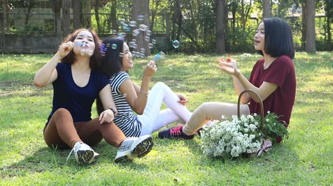 Three girls blowing soap bubbles in park. Stock Footage 58493018