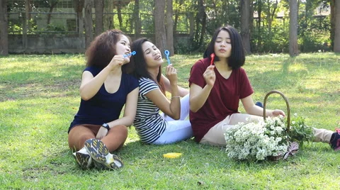 Three girls blowing soap bubbles in park. Stock Footage 58493341