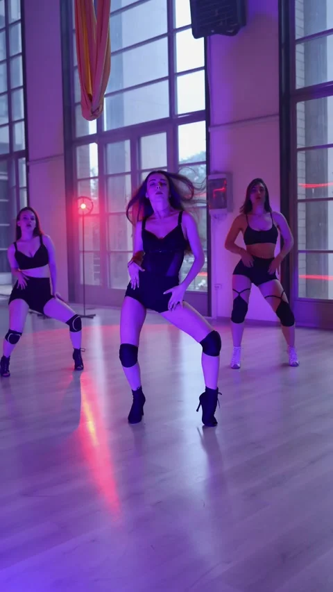 Three girls dancing in the studio under evening light. Sexy women's heels dance Stock Footage 277431296