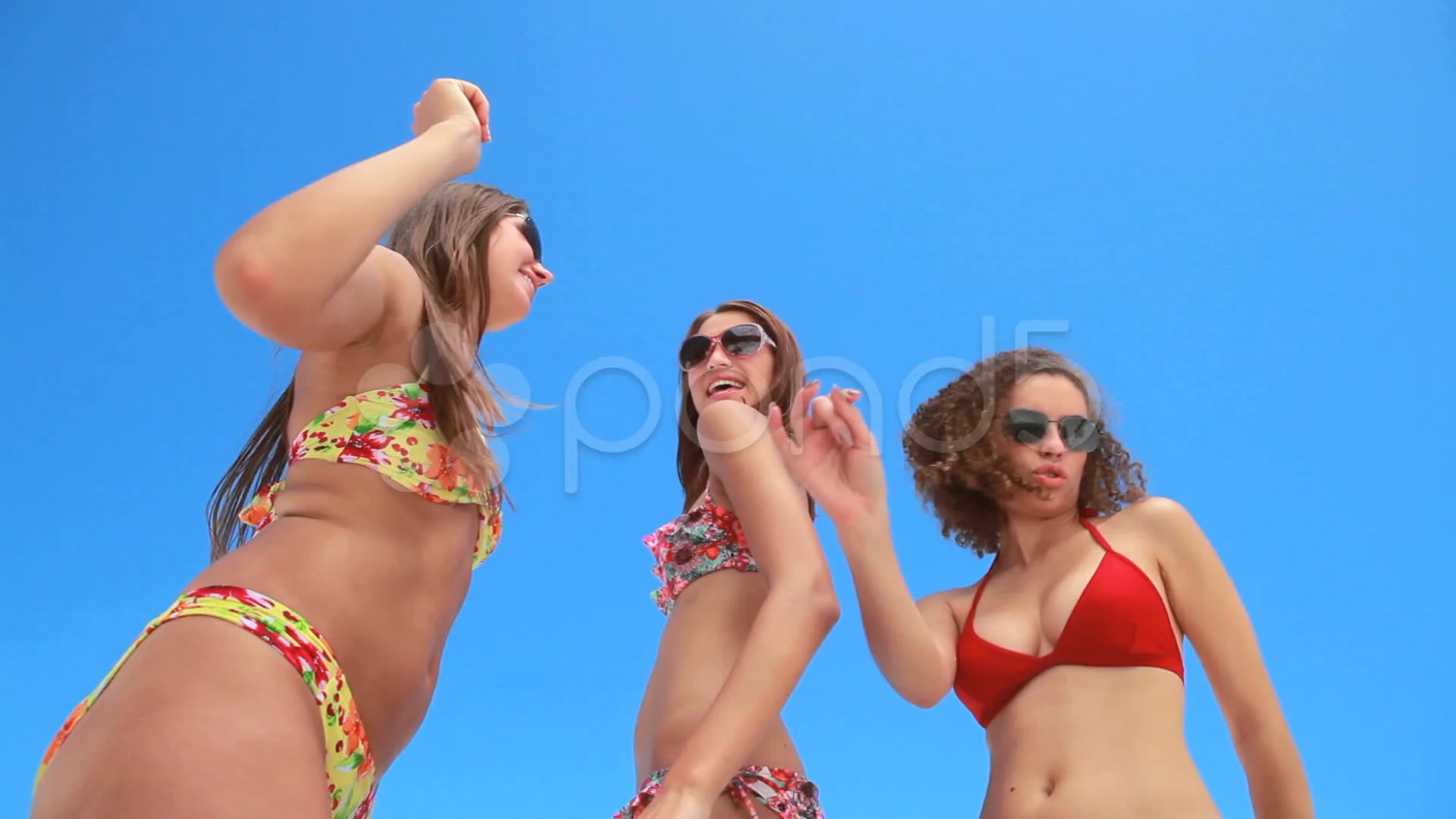 Three girls dancing together in bikinis