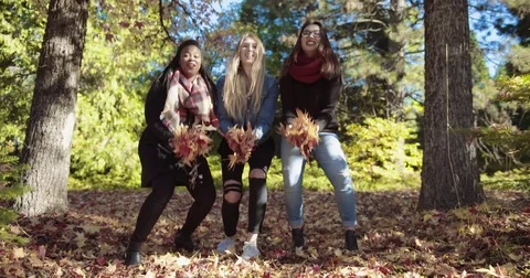 Three Girls of different ethnic backgrounds throwing leaves Stock Footage 70684531