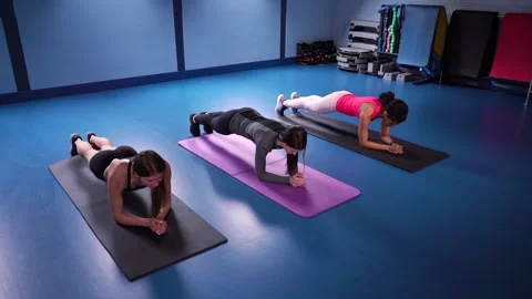 Three girls doing plank exercise on mats in gym Stock Footage 134187829