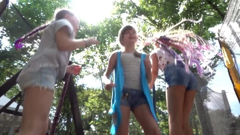 Three girls jump and have fun at the Trampoline on a Playground Summer Day Stock Footage