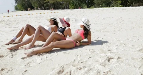 Three Girls Lying On Beach In Bikini And Straw Hats, Enjoy Sun Tan Talking Stock Footage