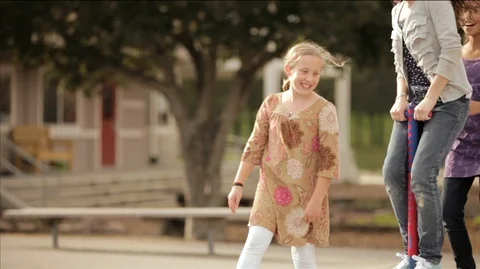 Three girls playing with a pogo stick at a playground. Vidéo 88342953