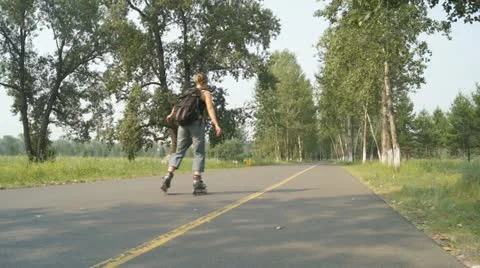 Three girls riding on rollers and a man biker in the park Stock Footage 11468652