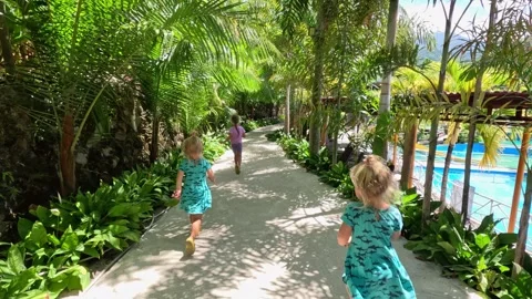 Three girls running between palm trees 库存影片 251986293