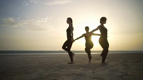 Three girls silhouette do eagle pose yoga in desert dawn Slow motion Rapid Stock Footage 79814846