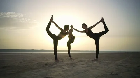 Three girls simultaneously warrior pose yoga in desert sunrise Slow motion Rapid Stock Footage 79814717