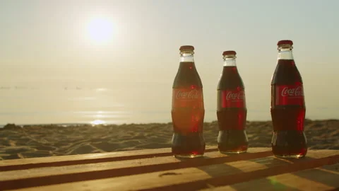 Three glass bottles of coca cola on the beach at sunrise. Stock Footage 205571967