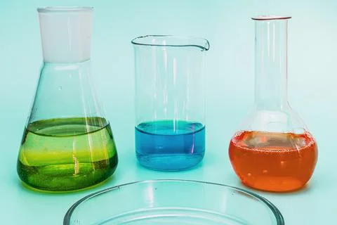 Three glass laboratory flasks with solutions of different colors. The concept Photos