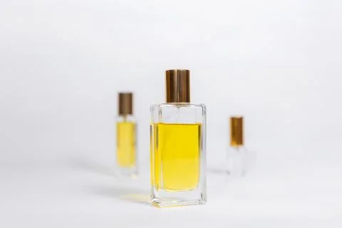 Three glass transparent rectangular bottles of golden perfume on white backgr Stock Photos