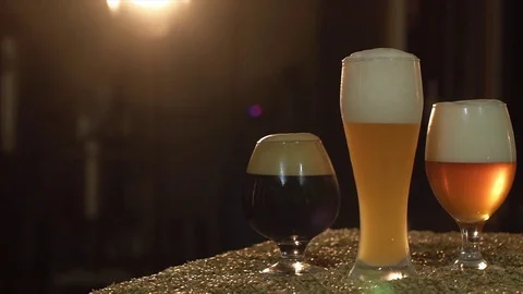Three glasses of beer stand on the table. The table is covered with malt Stock Footage 84043929