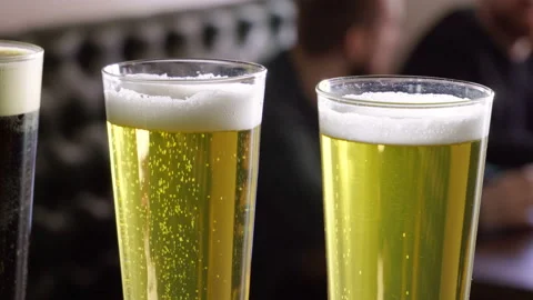 Three glasses of beer standing on the bar counter in a modern restaurant. 4K Video stock 90969355