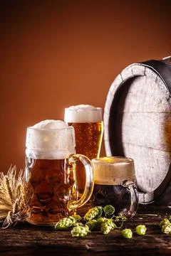 Three glasses with draft beer in front of a wooden barrel. Decoration of ba.. Stock Photos