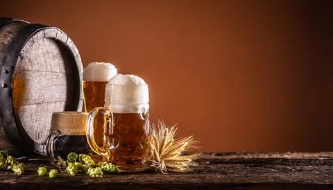 Three glasses with draft beer in front of a wooden barrel. Decoration of ba.. Stock Photos