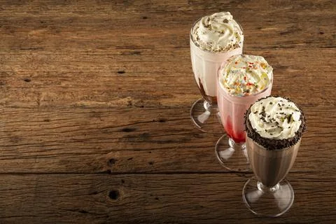 Three glasses of milkshake with assorted flavors. Chocolate, vanilla and st.. Stock Photos
