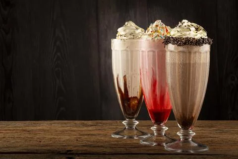 Three glasses of milkshake with assorted flavors. Chocolate, vanilla and st.. Stock Photos
