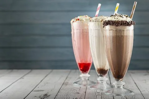 Three glasses of milkshake with assorted flavors. Chocolate, vanilla and st.. Stock Photos