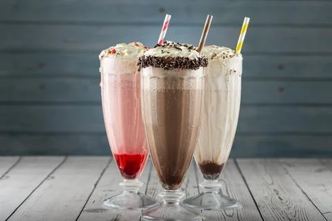 Three glasses of milkshake with assorted flavors. Chocolate, vanilla and st.. Stock Photos
