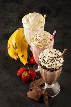 Three glasses of milkshake with assorted flavors. Chocolate, vanilla and st.. Stock Photos